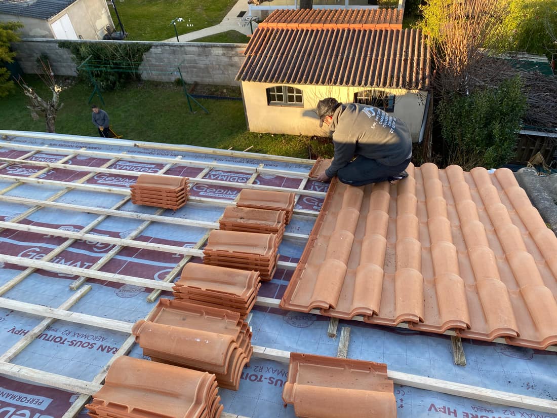 Pose de tuiles neuves sur écran sous-toiture lors d'une rénovation en Gironde